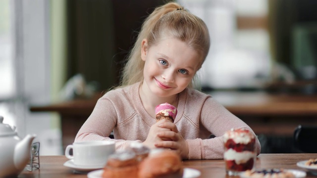 小女孩的肖像与冰淇淋短角在咖啡馆摆姿势。中近距离拍摄4k红色相机视频素材
