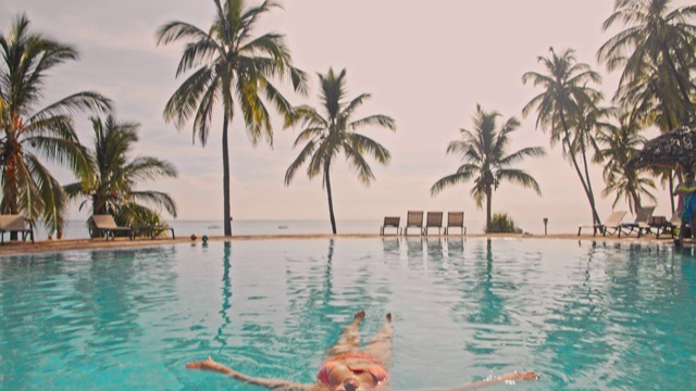 在一个豪华海滩度假胜地的游泳池里漂浮着的女人视频下载