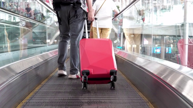 在机场的自动扶梯上拿着旅行袋的男人。视频素材