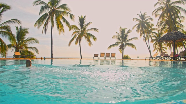 SLO MO女人跳进一个豪华海滩度假胜地的游泳池视频下载