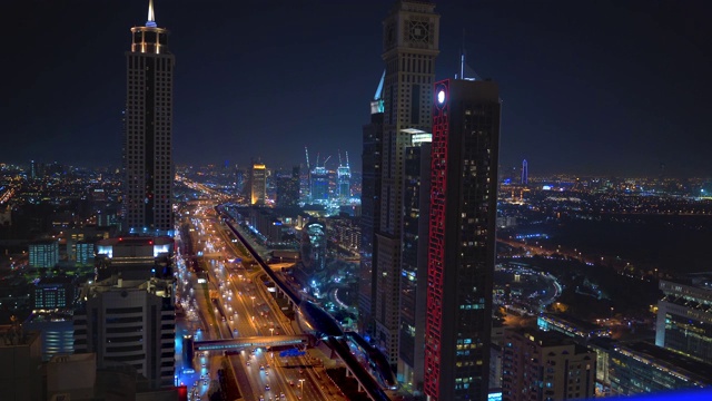 现代摩天大楼，夜晚被照亮的道路，豪华的迪拜市中心天际线，阿联酋。从屋顶俯瞰视频下载