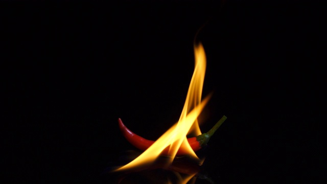 在黑色背景上用火燃烧红辣椒视频素材