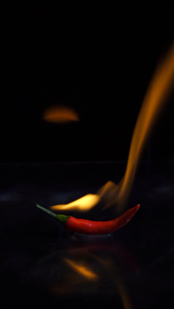 垂直:在黑色背景上用火燃烧红辣椒视频素材