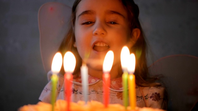 小女孩吹灭生日蛋糕上的蜡烛。特写镜头。缓慢的运动。视频素材