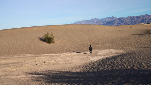在加州死亡谷梅斯奎特平原的沙丘上徒步旅行的妇女。视频下载