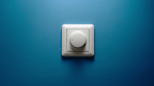 男性的手转动蓝色墙壁上的调光按钮视频下载