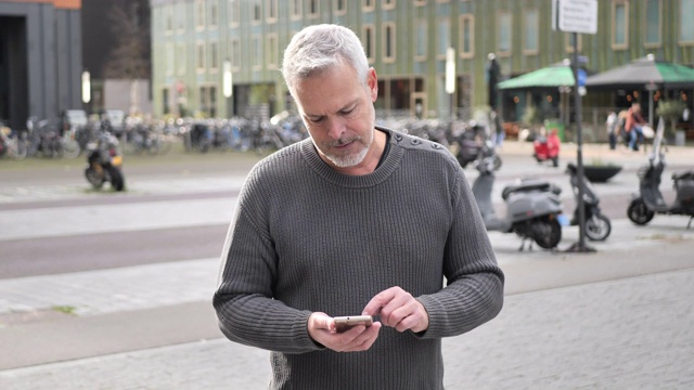 一个在户外用智能手机发信息的成熟男人视频素材
