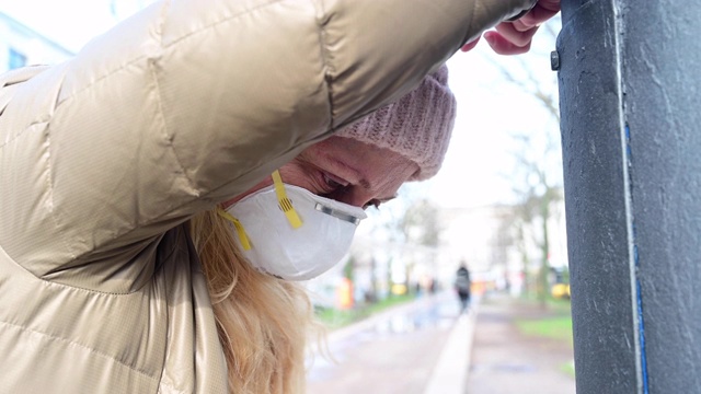 累坏了的女人躺在路边。她戴着防护面具。德国柏林。视频素材