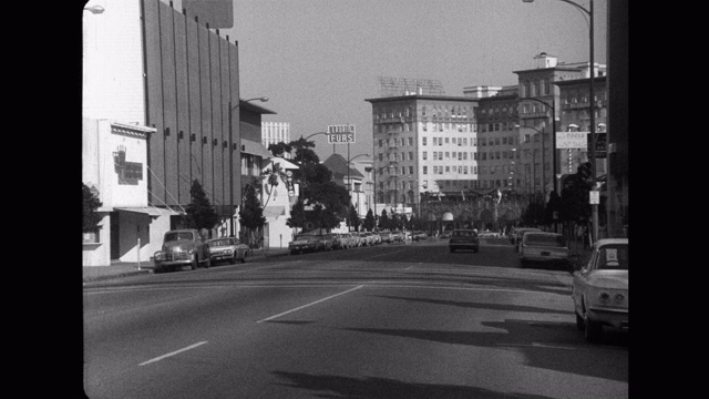 1960年-宽镜头汽车驾驶在罗迪欧大道，贝弗利威尔希尔酒店的背景，洛杉矶，加利福尼亚州，美国视频素材