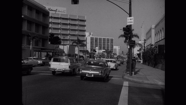 20世纪60年代的今天，美国加利福尼亚州洛杉矶市威尔希尔大道上开着宽镜头汽车视频素材
