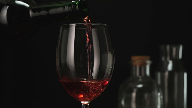 熟练的侍酒师将红酒从瓶中倒入玻璃杯。关闭了。视频素材