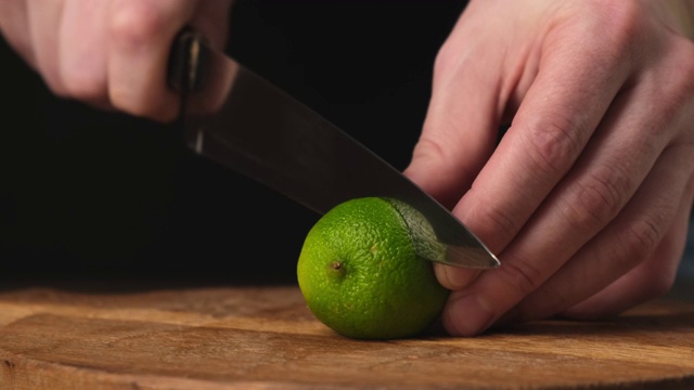 用刀将新鲜的酸橙切成两半，放在木砧板上。关闭了。视频素材