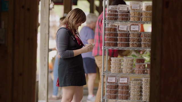 年轻的千禧一代妇女在农贸市场上看坚果的配料视频素材