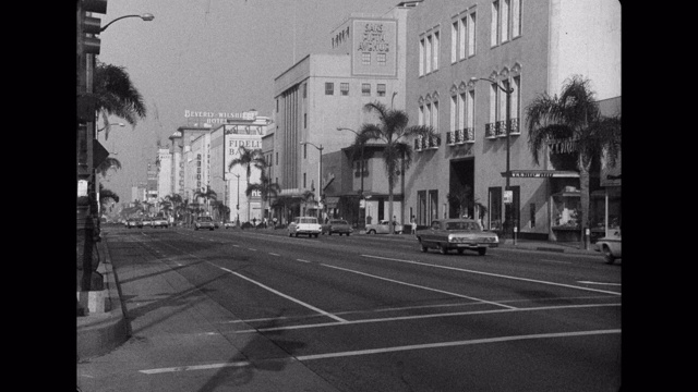 1960年代-汽车行驶在威尔希尔大道，比佛利山，洛杉矶县，美国加州视频素材