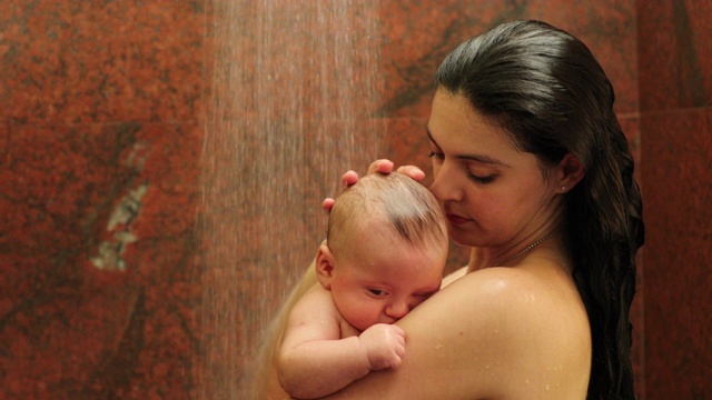 妈妈抱着新生婴儿在淋浴间洗澡和清洗婴儿视频素材