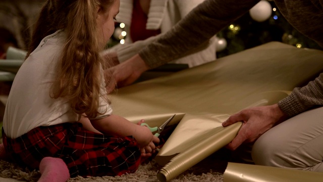 父母帮助孩子剪包装纸作为圣诞礼物视频素材