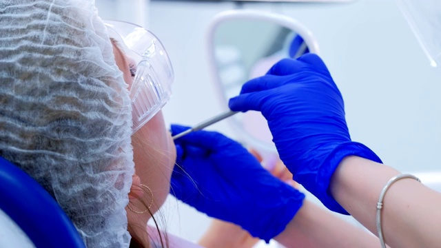 女病人在预防检查中在牙科椅上看镜子。视频素材