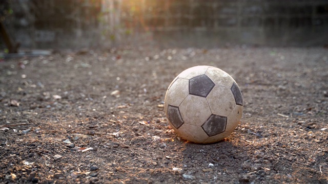 可怜的孩子玩或踢老足球或足球在地面上发光的阳光背景和希望的概念。视频购买