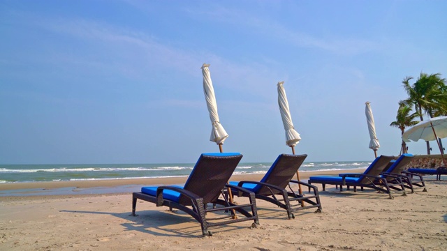 空的沙滩椅子在海滩与大海和蓝天的背景视频素材