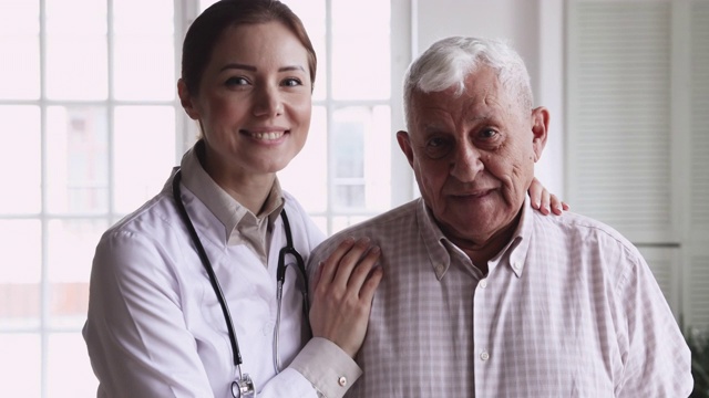 微笑的女医生抱着开心的老病人看镜头视频下载