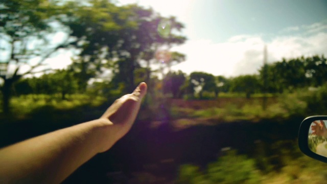 一个女人的手在微风中的观点拍摄在一个阳光明媚的公路旅行视频素材