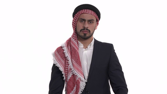 特写的年轻的胡子阿拉伯男子穿着keffiyeh站，交叉他的双臂在胸前。肢体语言和手势概念。孤立，在白色背景上视频下载