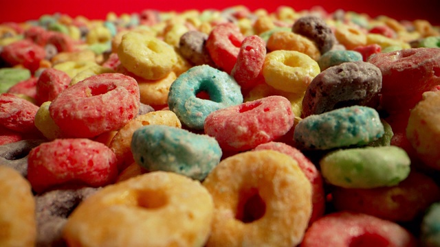 微距特写广角移动拍摄的糖彩色水果环美国早餐麦片摊开在一个红色的背景视频素材