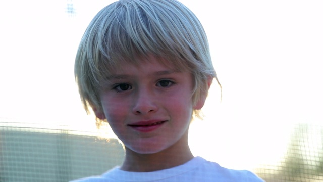 小男孩的肖像微笑与镜头耀斑阳光户外英俊的小男孩视频素材