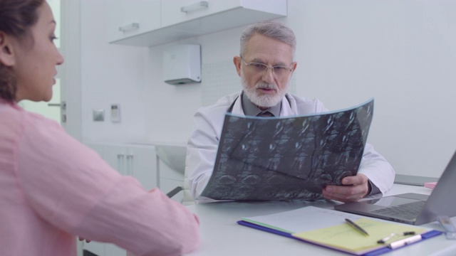 男医生分析核磁共振图像，与病人交谈，保健，诊所视频素材