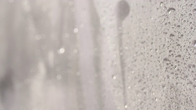 淋浴时水滴在玻璃上。水流在浴室的玻璃墙上，没人。4k动态视频，3840x2160视频素材