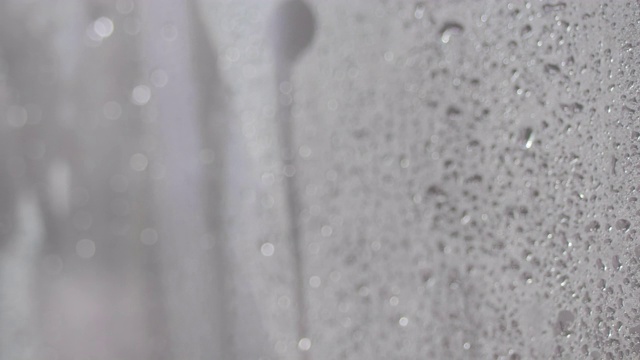 淋浴时水滴在玻璃上。水流在浴室的玻璃墙上，没人。4k动态视频，3840x2160视频素材
