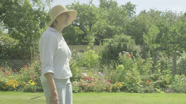 一位年长的白人妇女走过她的花园视频下载
