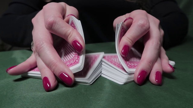 涟漪洗牌。女人的手涂着红色指甲油，洗牌。特写，赌场，碰运气的游戏视频素材