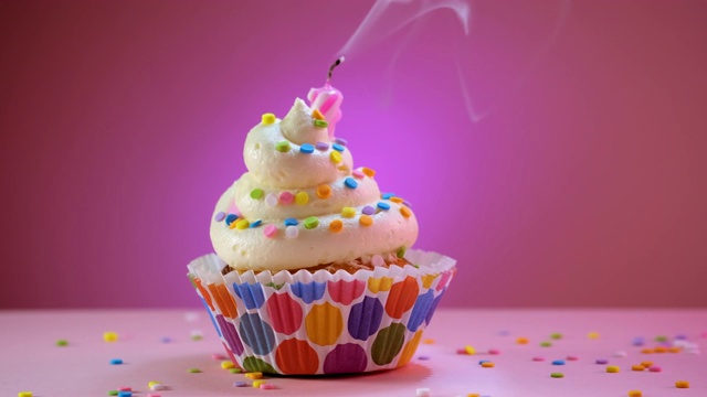 吹灭用糖屑装饰的生日蛋糕的蜡烛视频素材