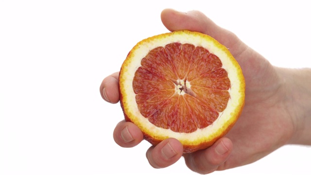 男性的手拿着一片成熟的血橙的特写。多汁的柑橘类的水果。孤立，在白色背景上视频素材