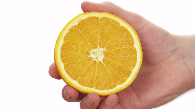 一名男子压榨半只熟透多汁的橙子的微距镜头。柑橘汁滴下来。孤立，在白色背景上视频素材