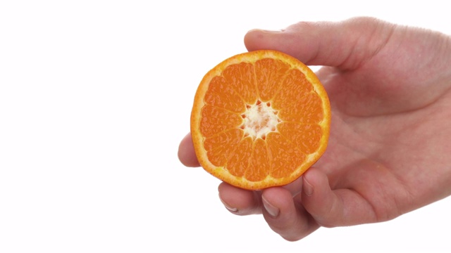 特写的男性手握和挤压一半成熟多汁的克利奥帕特拉桔子。柑橘汁滴下来。孤立，在白色背景上视频素材