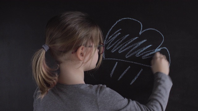 小女孩在黑板上画云视频素材