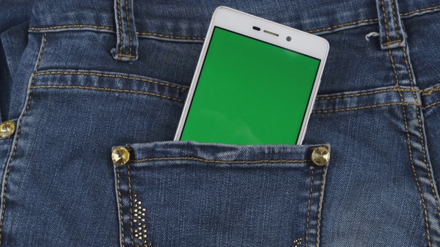 变焦。一个绿色屏幕的智能手机从牛仔裤口袋里伸出来。的概念。视频下载