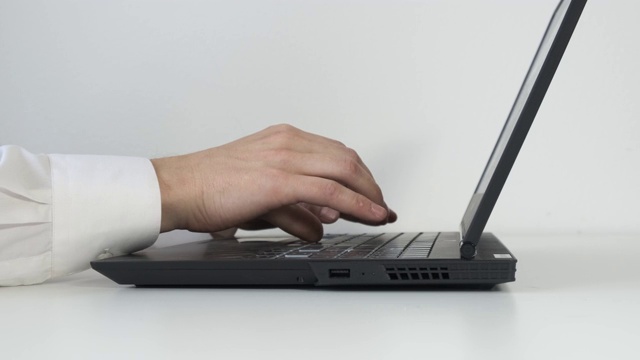 在办公室用笔记本电脑键盘打字。白色的桌子。视频下载