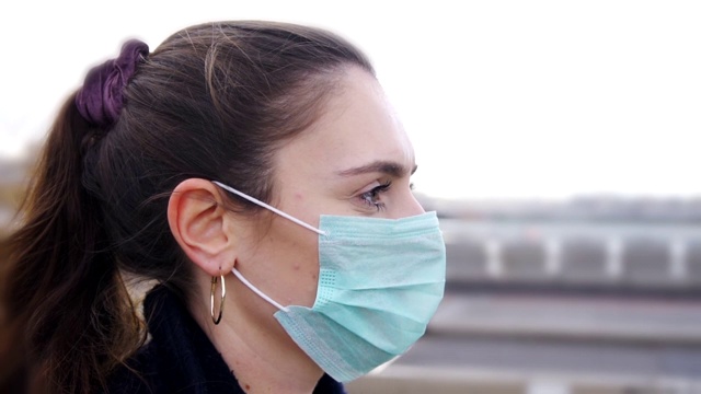 年轻女子的侧面戴着面具，而走在伦敦的街道上视频素材