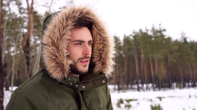 有魅力的大胡子男子站在户外的冬季森林。视频素材