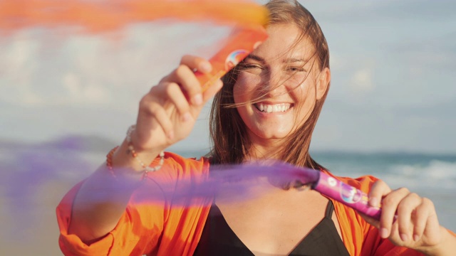 美丽的年轻女子玩烟雾弹庆祝大海的肖像。慢动作视频。视频素材