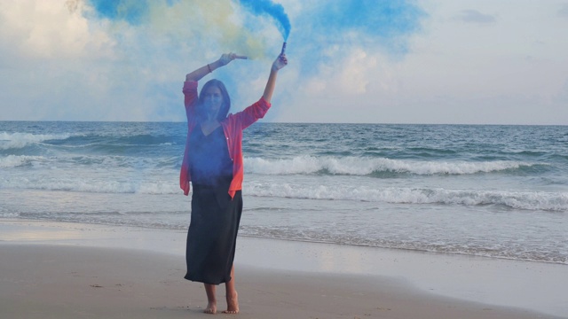 美丽的年轻女子玩烟雾弹庆祝大海的肖像。慢动作视频。视频素材