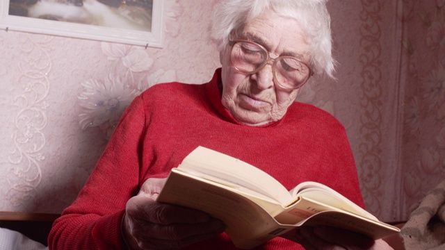 祖母戴着眼镜看书。视频素材
