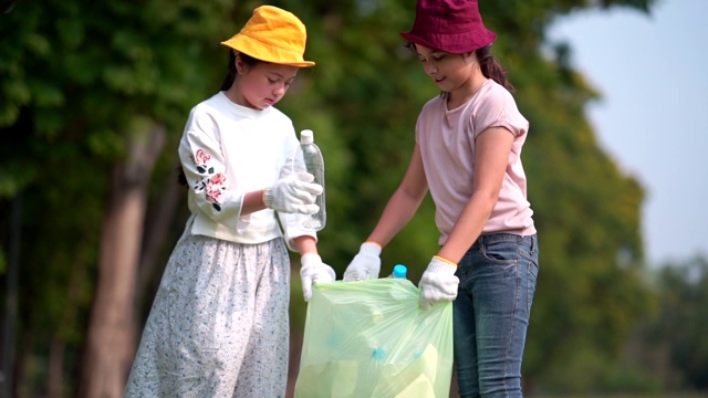 女孩和朋友帮助清理公园，捡起或垃圾收集地面上的垃圾视频素材