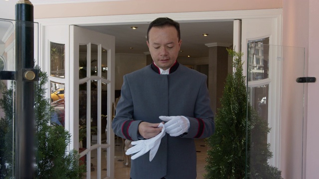 在酒店里，友善的侍者把手套作为制服的一部分，对着镜头微笑视频下载