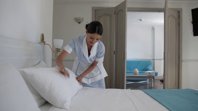 拉丁美洲女清洁工在酒店微笑着做床视频下载