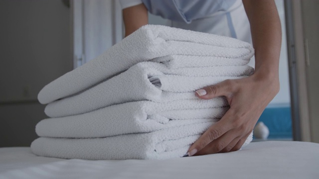 关注女清洁工为客人在床上留下干净毛巾的前景视频素材