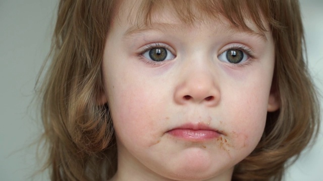 3岁女孩吃巧克力大胃口的白人女孩肖像的特写。孩子被巧克力弄脏了。视频素材
